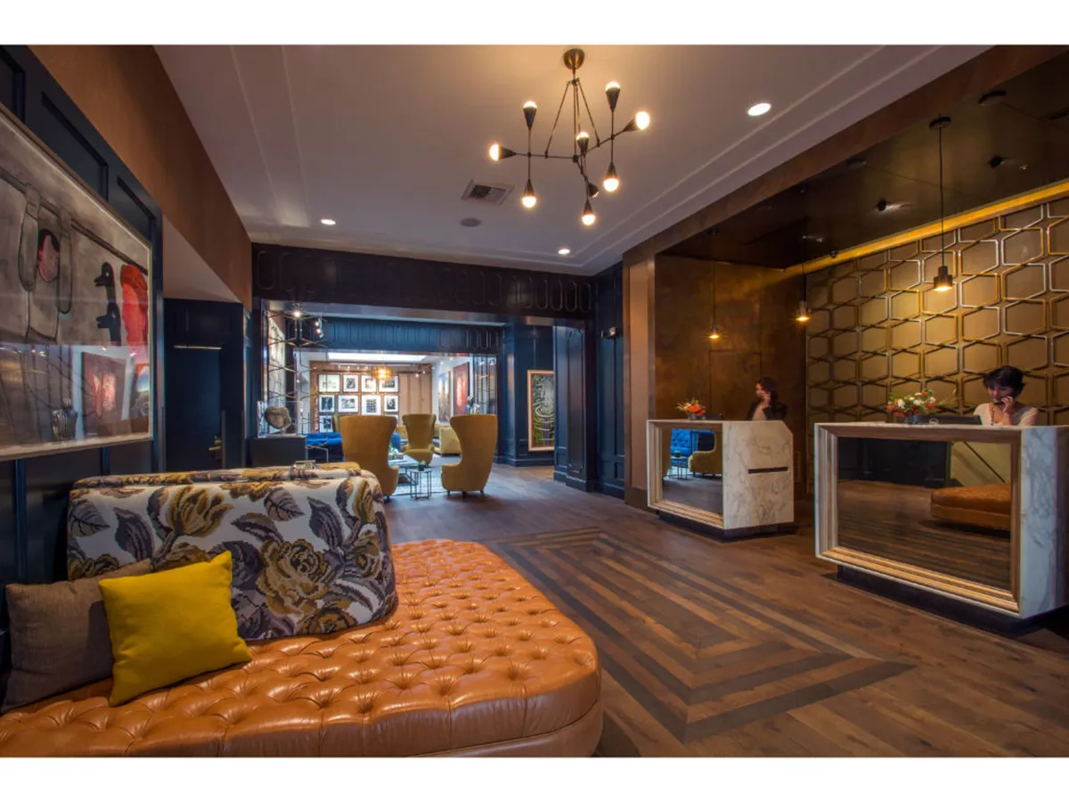 A contemporary and welcoming lobby space with stylish seating, a reception desk, and prominent artwork adorning the walls. The layout encourages social interactions and serves as a first impression for guests entering the hotel.