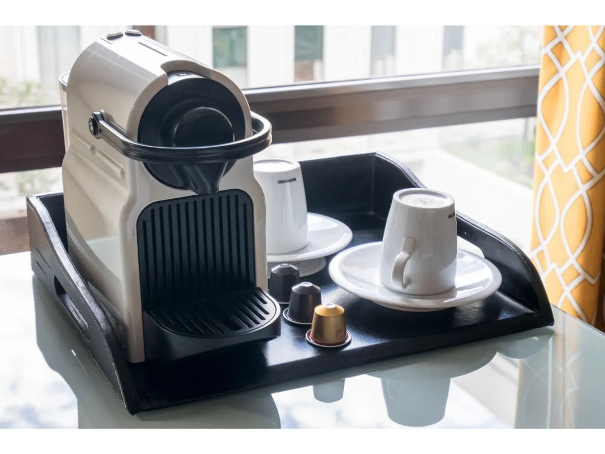 A close-up of the in-room Nespresso coffee machine on a sleek black tray, accompanied by coffee cups and capsules. The arrangement invites guests to enjoy a fresh brew in the privacy of their room, setting the stage for a restorative morning or cozy evening.